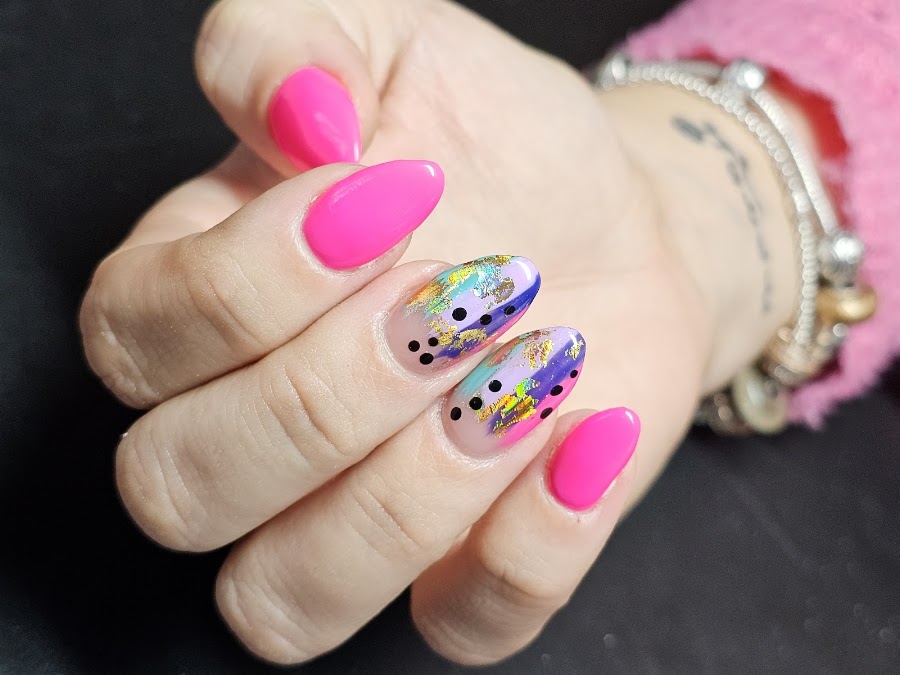Neonroze nagels met goudfolie en stipjes.
