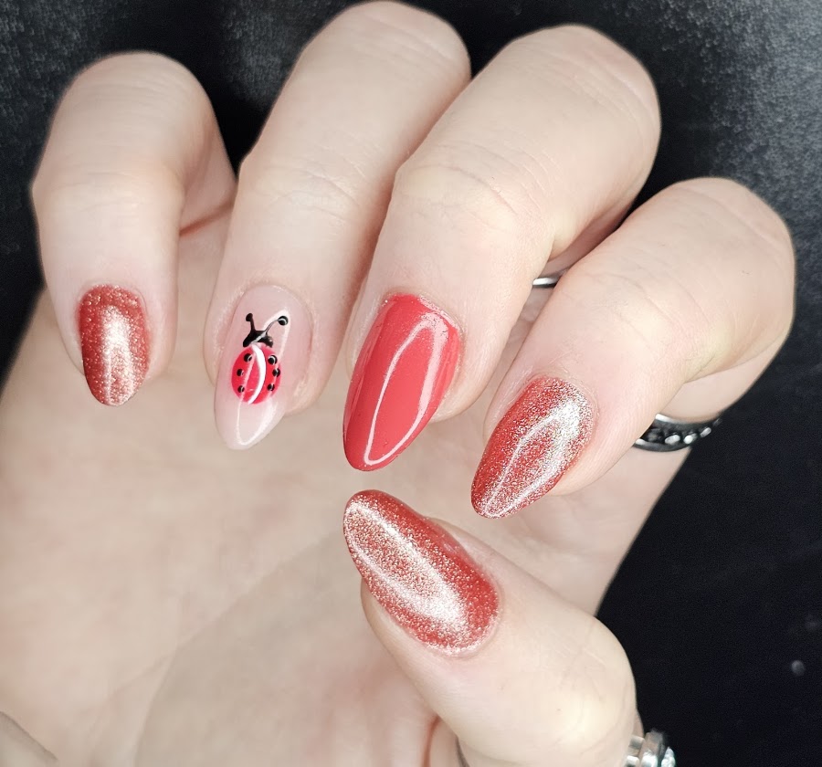 Rode nagels met glitter en een handgeschilderd lieveheersbeestje.